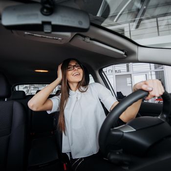 Pretty young woman driving her new car