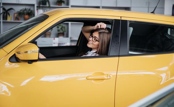 attractive young Caucasian woman looking at the camera from the front seat of the car