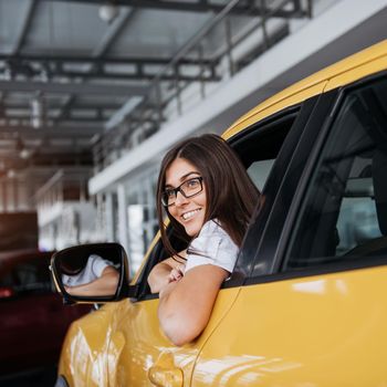Young woman in her new car smiling.
