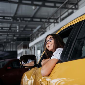 Young woman in her new car smiling.