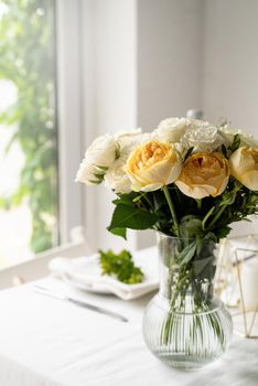 beautiful table setting for romantic dinner for two, with Linen napkins , white roses and boxwood. Close up roses bouquet copy space