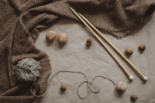 hobby, leisure theme. Yarn and wooden needles on a brown paper texture background with cozy warm plaid, top view, copyspace.