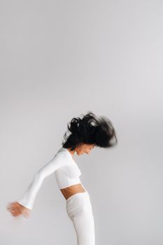 A blurry silhouette of a woman in white sportswear is engaged in dynamic kali meditation in the yoga hall.