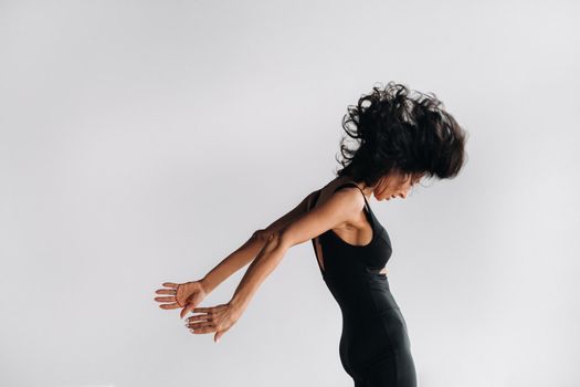 A woman in black sportswear is engaged in dynamic kali meditation in the Yoga hall.