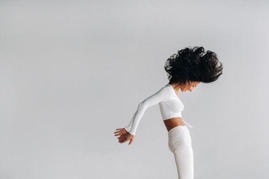 A woman in white sportswear is engaged in dynamic kali meditation in the yoga hall.