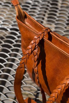 close-up photo of orange leather bag on a metal texture background. outdoor photo