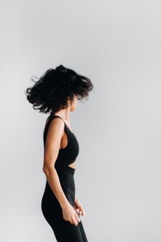 A blurry silhouette of a woman in black sportswear is engaged in dynamic kali meditation in the yoga hall.