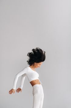 A woman in white sportswear is engaged in dynamic kali meditation in the yoga hall.