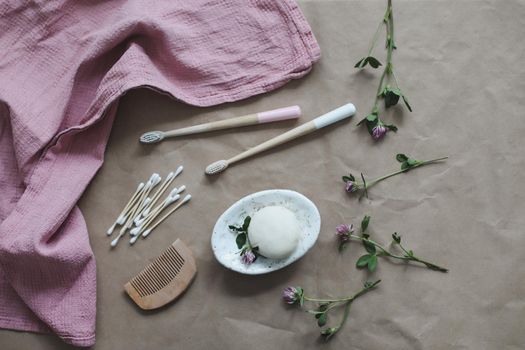 Handmade natural soap, wooden toothbrushes, cotton swabs and hairbrush on craft paper background top view with copyspace. Concept of plastic free and eco friendly products in household, top view