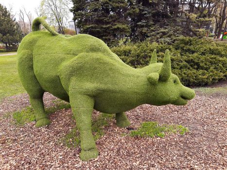 Decorative sculpture of a bull in a city park close-up.