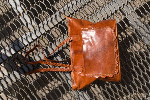 close-up photo of orange leather bag on a metal texture background. outdoor photo