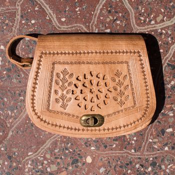 small yellow women's leather bag with a carved pattern. street photo