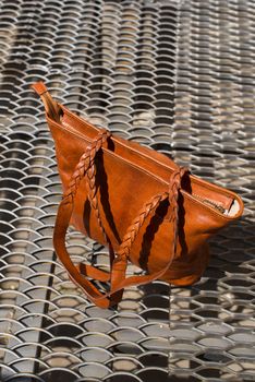 close-up photo of orange leather bag on a metal texture background. outdoor photo