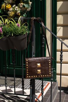 small brown women's leather bag with rivets. outdoors photo