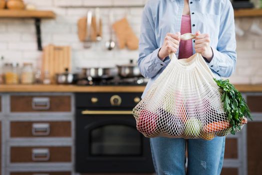 adult woman holding reusable bag with organic vegetables