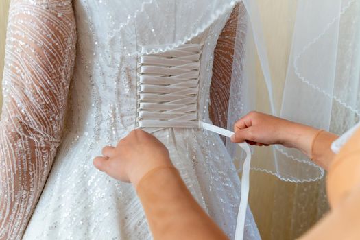 The bride helps to dress in a wedding dress. Lacing.