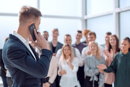 business man with smartphone pointing at a group of young people. photo with copy space