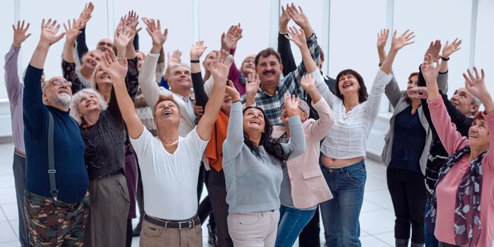 a group of elderly people are reaching up