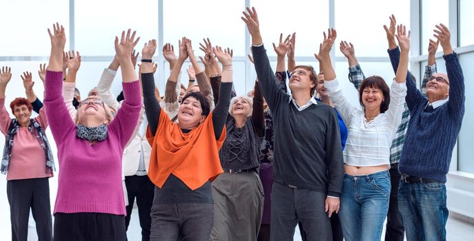 a group of elderly people are reaching up