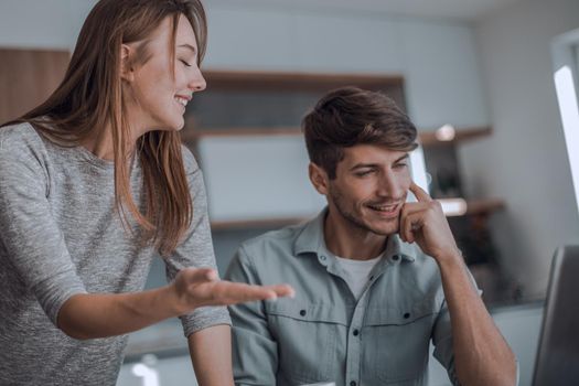 Young couple looking discussing online news in the kitchen. people and technology