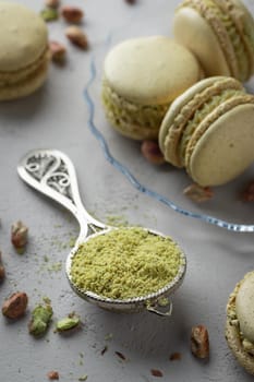 Pistachio flour and green macaroons on a gray background