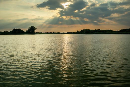 The sun behind the clouds over the lake, Stankow, Poland
