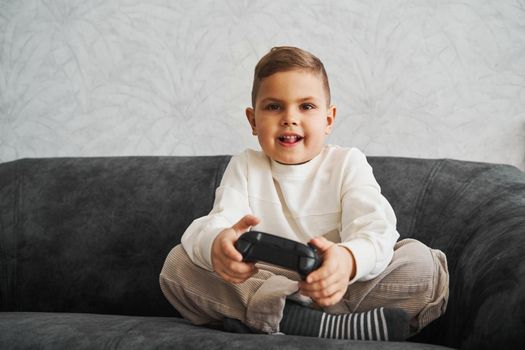 Happy child with gamepad at home. Boy is playing games