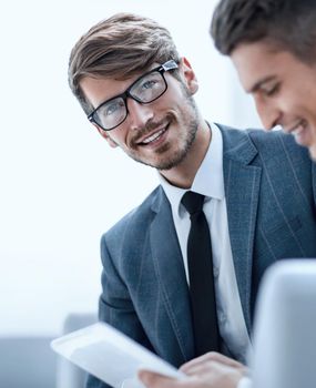 Smiling young businessman discussing something positive with his colleague, and using a digital tablet together