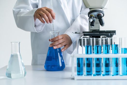 Woman scientist working in laboratory and examining biochemistry sample in test tube. Science technology research and development study concept.
