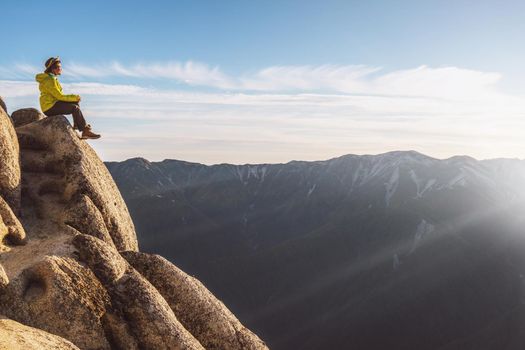 Epic adventure of brave and ambitious hiker trekking activity on wild cliff, pose with panoramic nature mountain landscape. Winner motivation and power discovery travel concept.