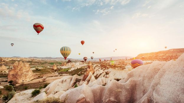 Hot air balloon flying over rock landscape at Cappadocia Turkey. Valley, ravine, hills, located between the volcanic mountains in Goreme National Park.