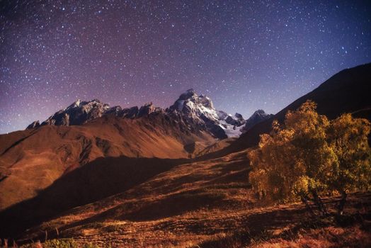 Fantastic starry sky. Autumn landscape and snow-capped peaks. Main Caucasian Ridge. Mountain View from Mount Ushba Meyer, Georgia. Europe