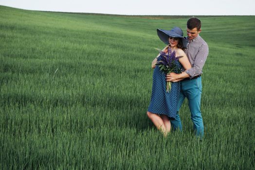 Happy couple awaiting baby. Beautiful and young parents at a photo shoot in a field of wheat