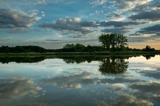 Reflection of clouds in the water and trees on the horizon, Stankow, Poland