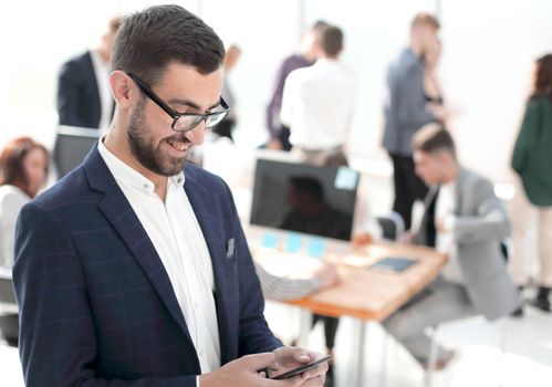 close up. smiling businessman reading correspondence on his smartphone. photo with copy space