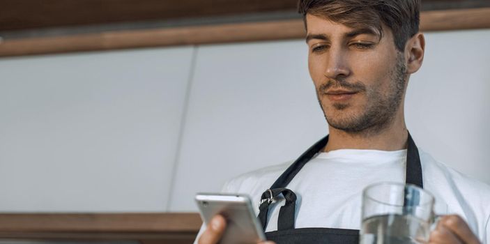 attractive young man reading a recipe on his smartphone. photo with copy space
