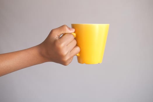close up of man hand holding yellow color mug .