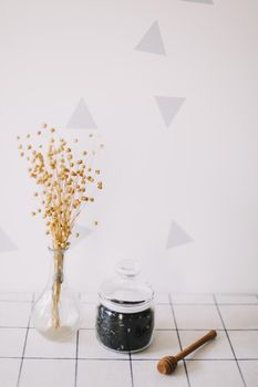 Dry black tea in glass jar and honey spindle on kitchen background. Hot drink in cold period.