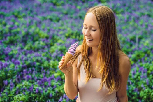 Young woman eats lavender ice cream on a lavender field background.