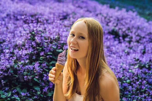 Young woman eats lavender ice cream on a lavender field background.