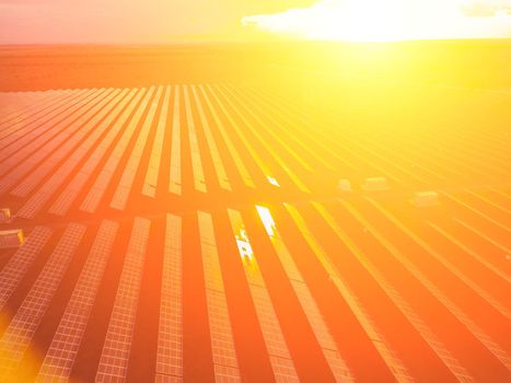 Aerial top view of a solar panels power plant. Photovoltaic solar panels at sunrise and sunset in countryside from above. Modern technology, climate care, earth saving, renewable energy concept