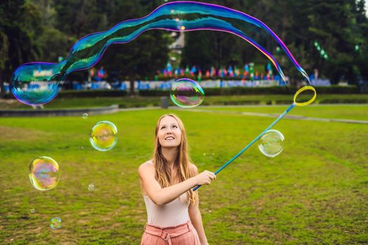 Happy carefree young woman blowing soap bubbles.