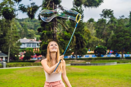 Happy carefree young woman blowing soap bubbles.