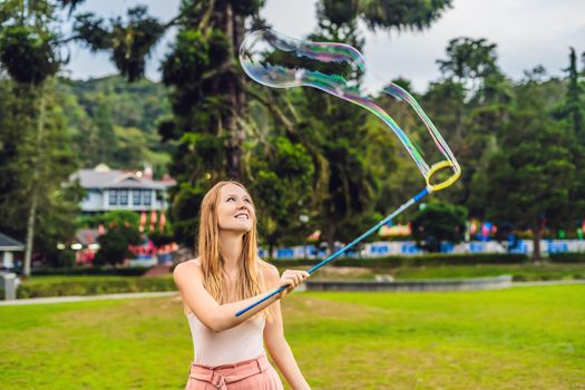 Happy carefree young woman blowing soap bubbles.