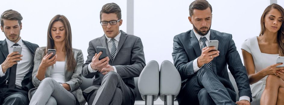 business colleagues with their smartphones sitting in the office hallway.people and technology