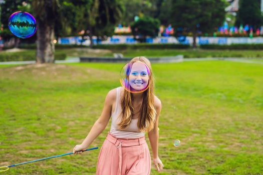 Happy carefree young woman blowing soap bubbles.