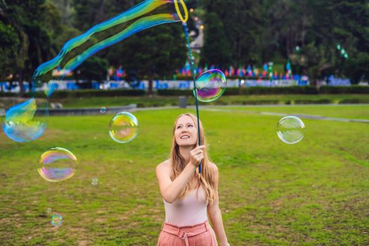 Happy carefree young woman blowing soap bubbles.