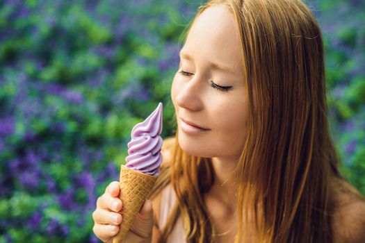 Young woman eats lavender ice cream on a lavender field background.