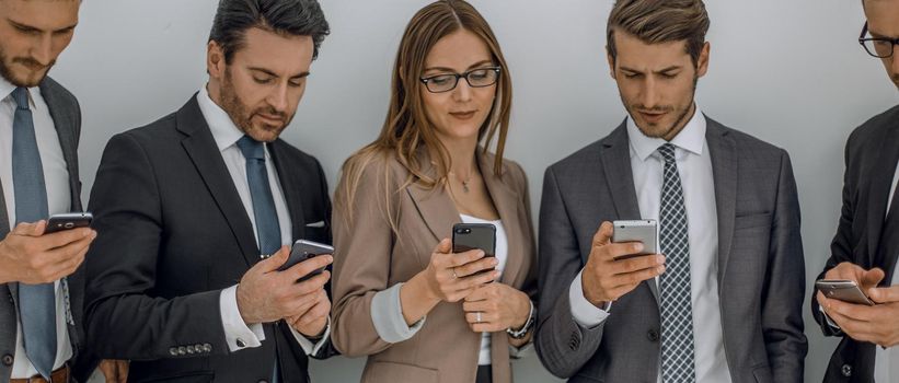 group of business people looking at the screens of their smartphones. people and technology