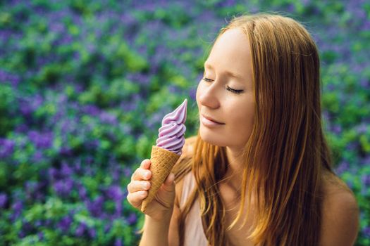 Young woman eats lavender ice cream on a lavender field background.